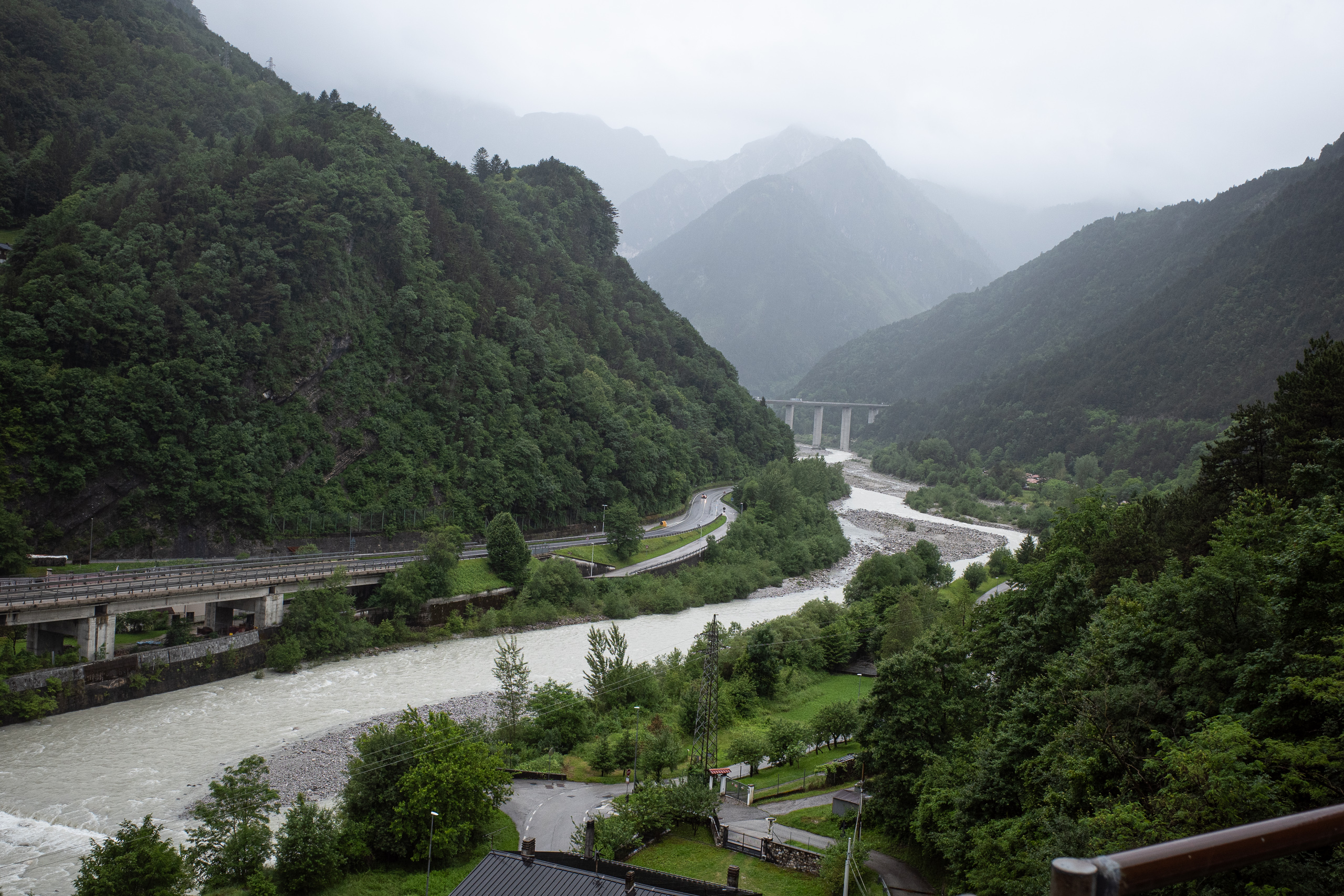 Nebelverhangene Berge über dem Tal, in der Ferne das Autobahnviadukt